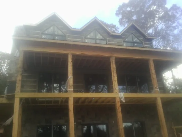 Dormers and porch framing on a large log home under construction — Roof Coating work by our crew in Powderly