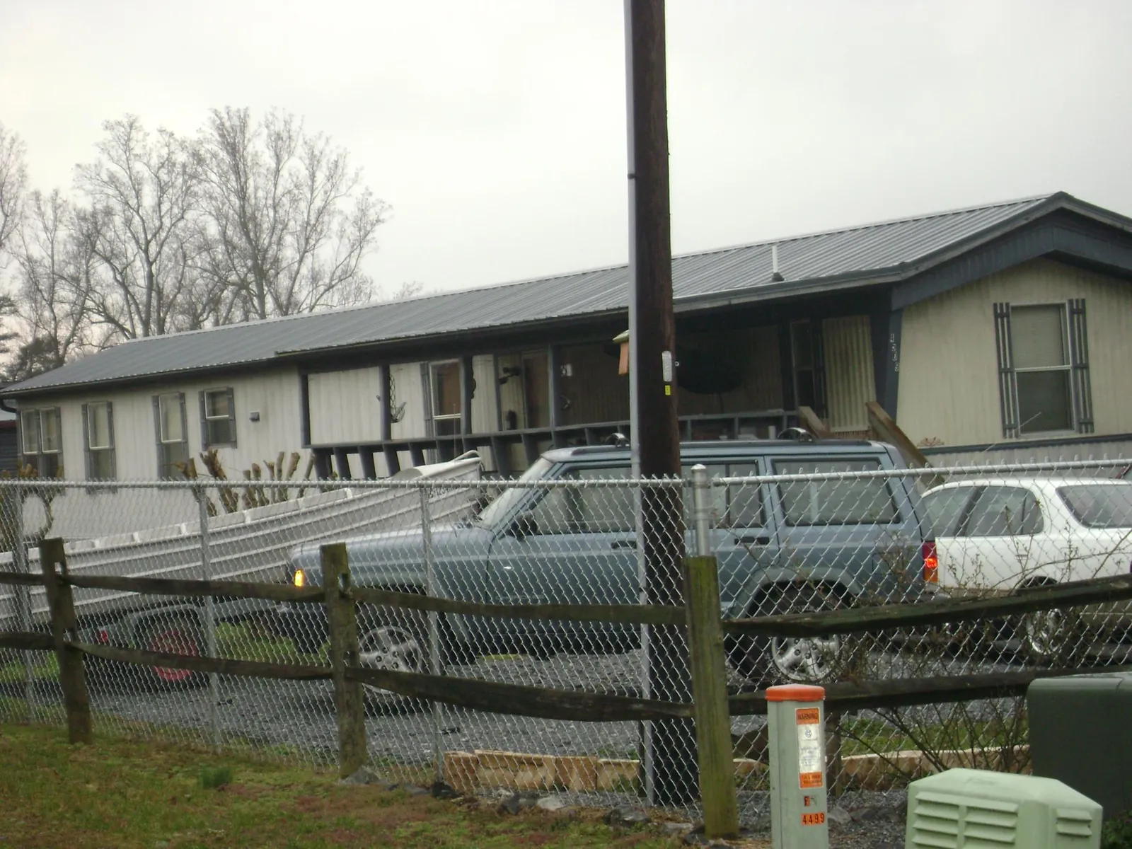 Dark metal roof on a long single story building behind a chain link fence in Powderly