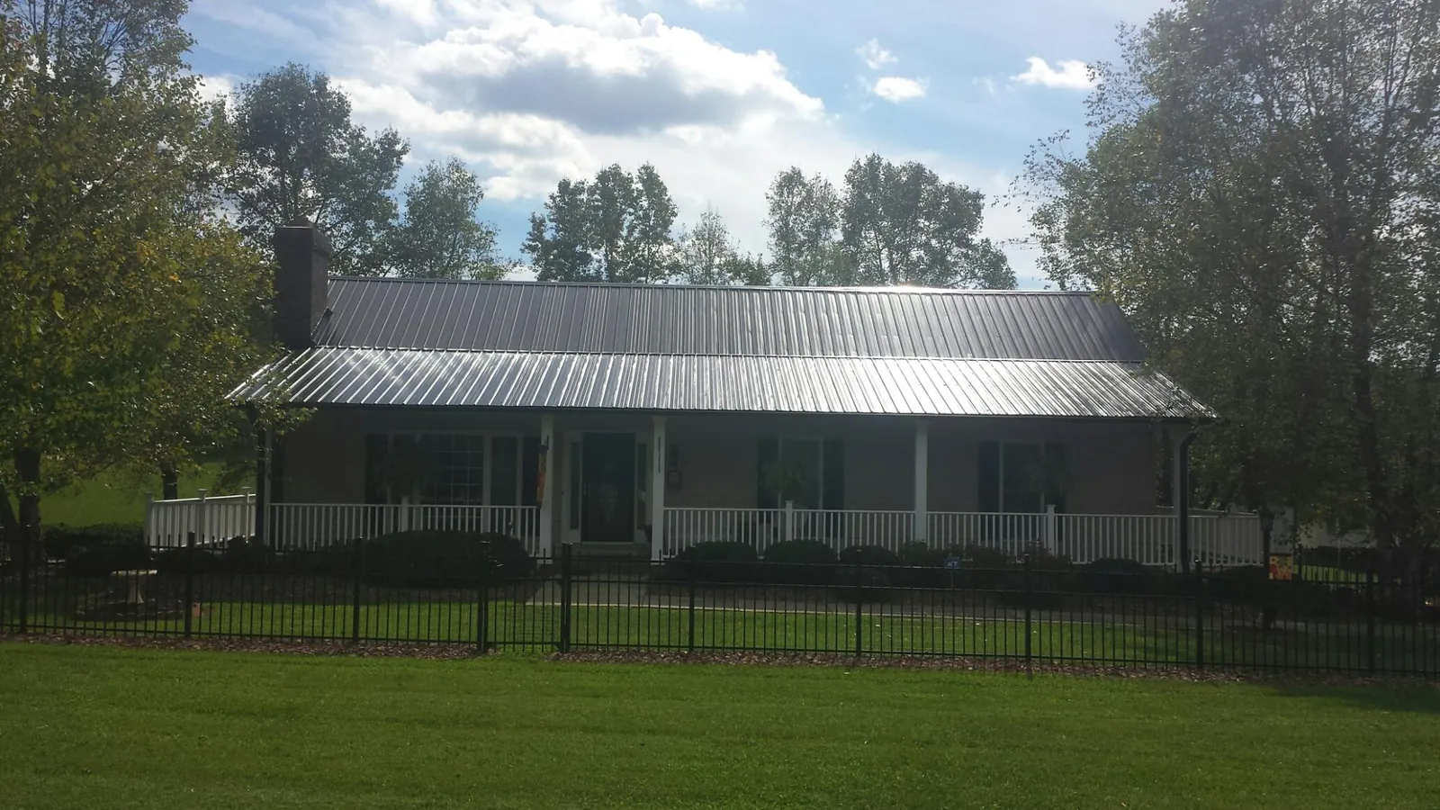 Gray metal roof on a brick ranch with a full width front porch — Gutter Guard Installation work by our crew in Powderly