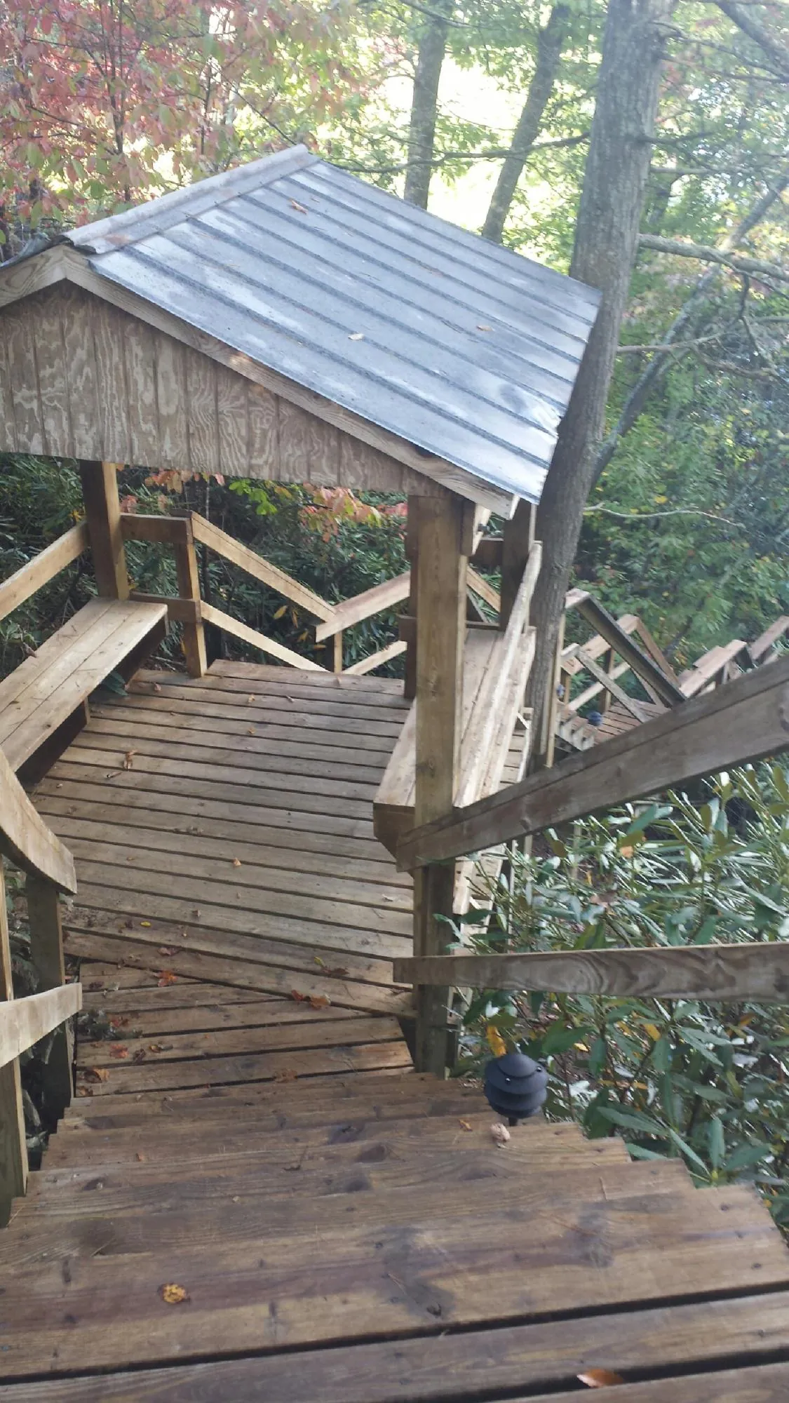 Metal roofed shelter over wooden steps on a wooded walkway — Skylight Repair & Installation work by our crew in Powderly