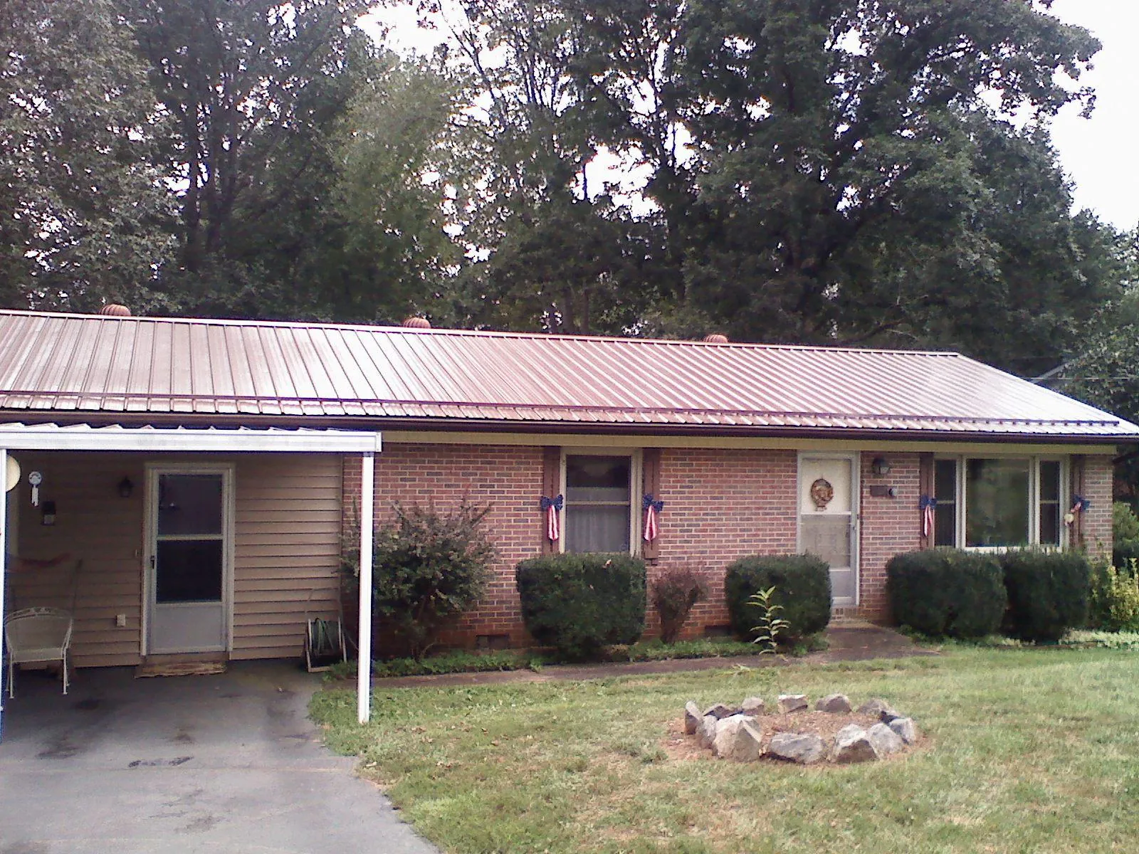 Bronze metal roof and carport on a brick ranch home — Roof Repair work by our crew in Powderly