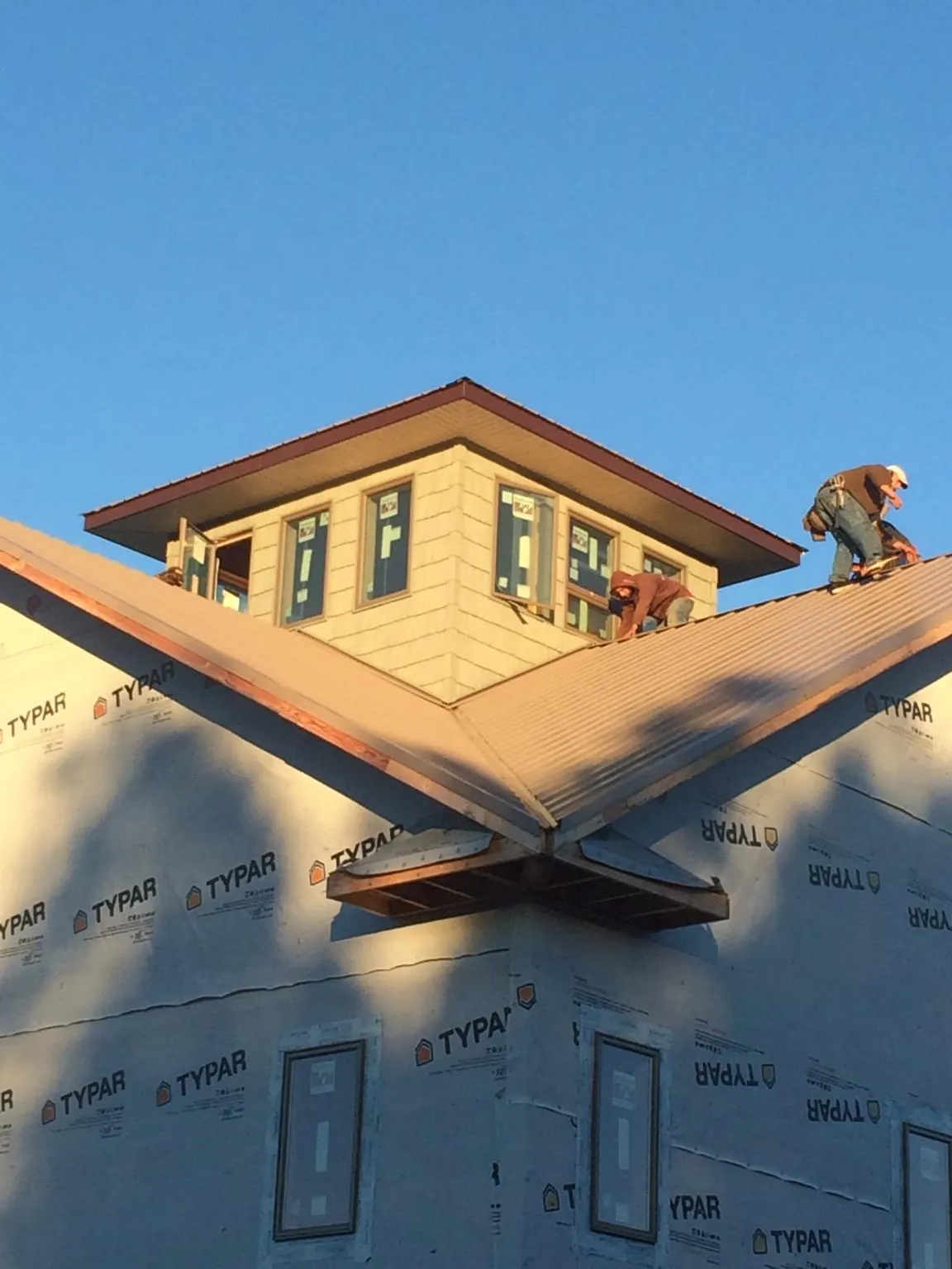 Roofers working around a rooftop cupola on a new metal roof at sunset — Roof Waterproofing in Powderly by Roofing Brothers